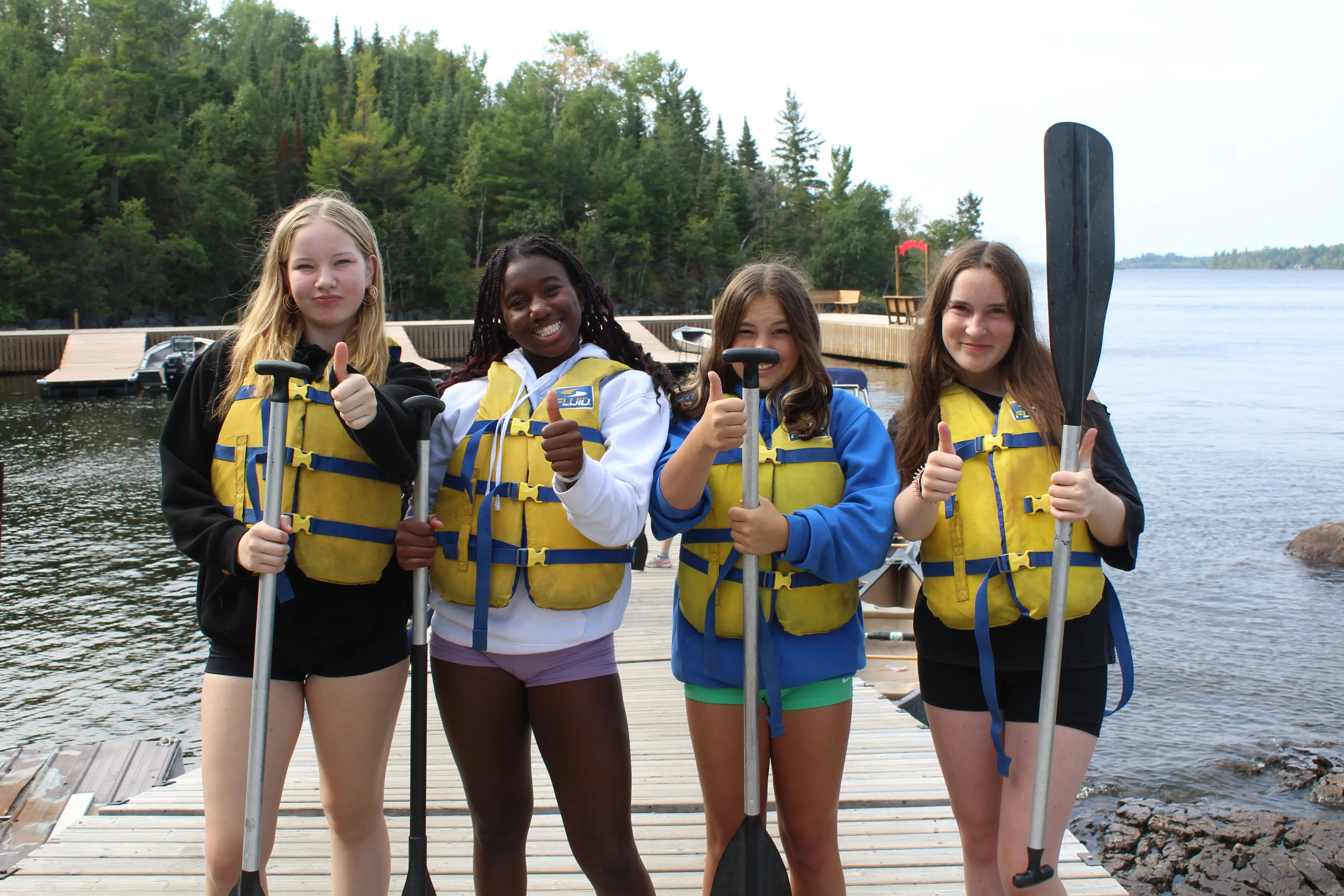 a group of girls wearing life jackets and holding paddles